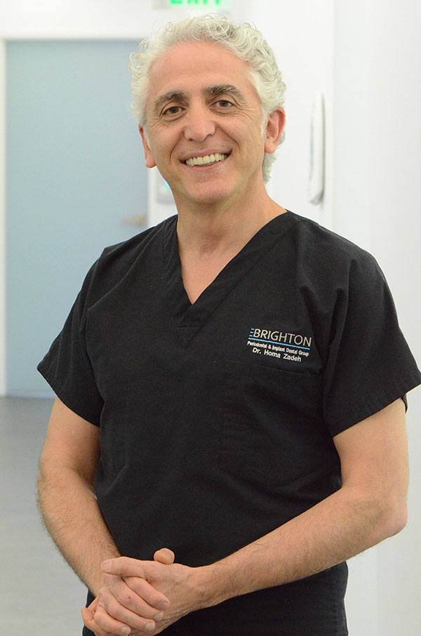 Dr. Homa Zadeh, wearing Brighton Dental group scrubs, smiling